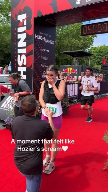 Man proposing to a woman at a race finish line.