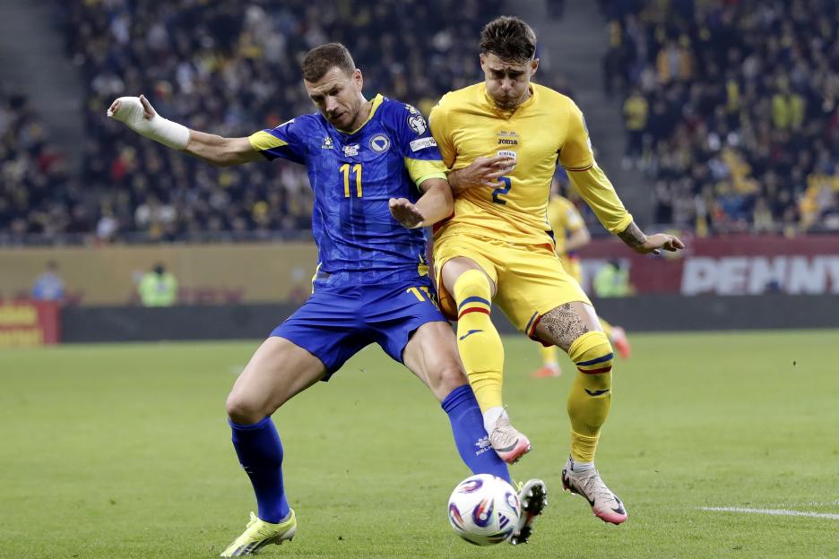 Bosnia and Herzegovina's Edin Dzeko and Romania's Andrei Ratiu vying for the ball during a soccer match.