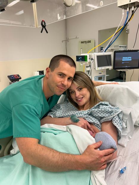 Parents holding their newborn baby in a hospital room.