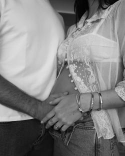 Black and white photo of a pregnant woman and a man holding her belly.