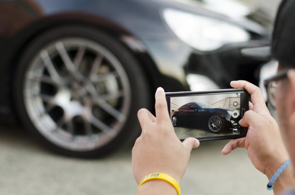 Person taking a picture of a car with a smartphone.