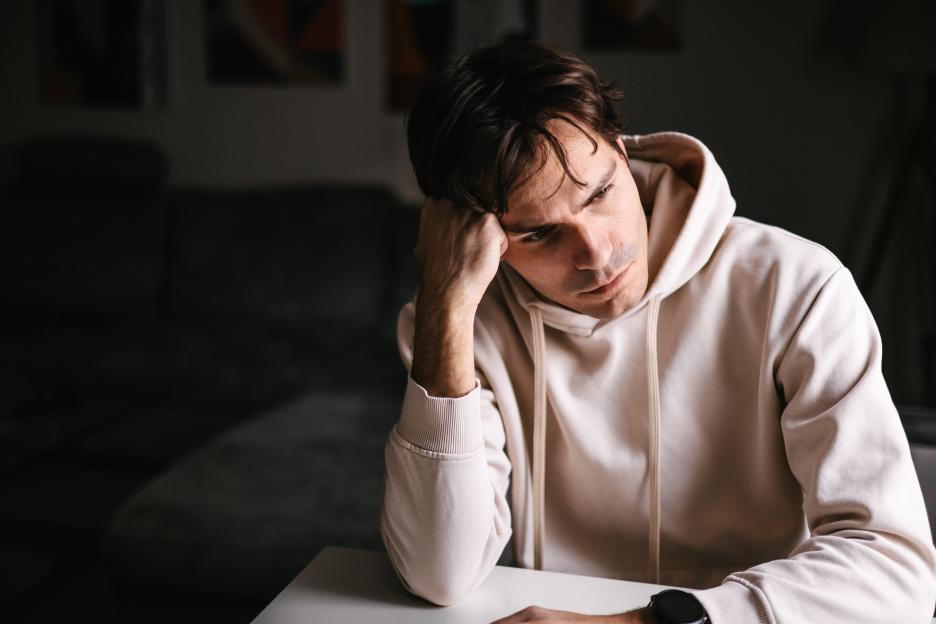 A man sits alone, looking worried.