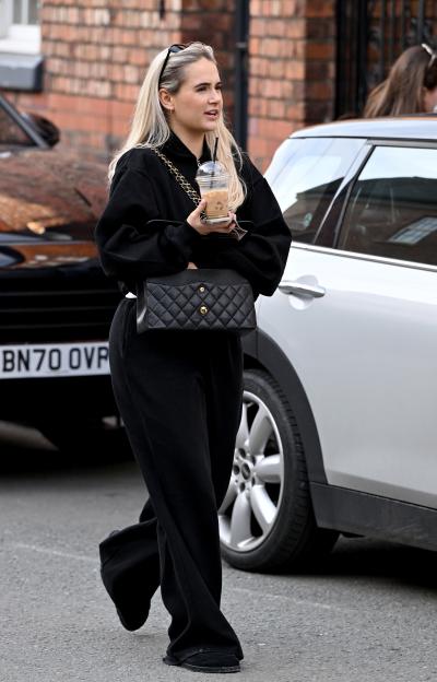 Molly-Mae Hague walking down the street, carrying a coffee and a bag.