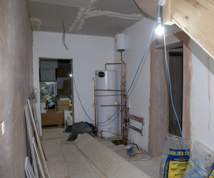 Unfinished home interior with exposed pipes and wiring.