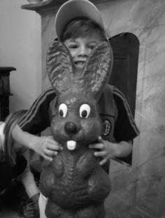 Black and white photo of a boy holding a large rabbit statue.