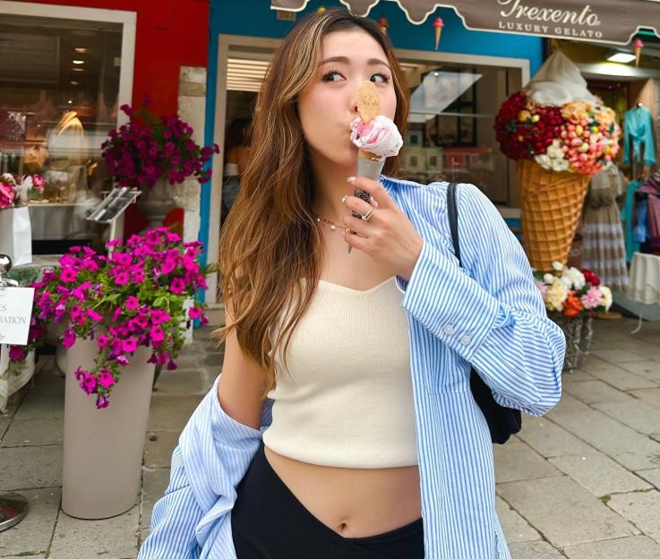 a woman eating an ice cream cone in front of a store called trecento