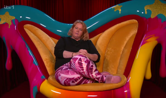 Woman sitting in a colorful, abstract chair.