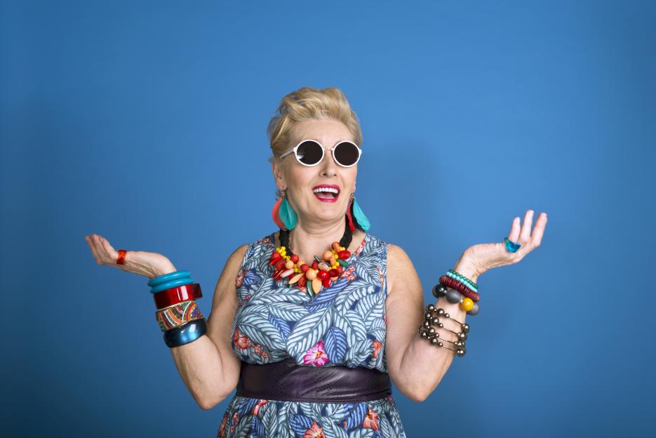 Portrait of a stylish senior woman wearing sunglasses and colorful jewelry.