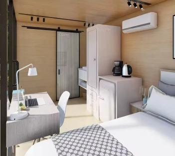 Illustration of a tiny home interior with a bed, desk, and small kitchen area.