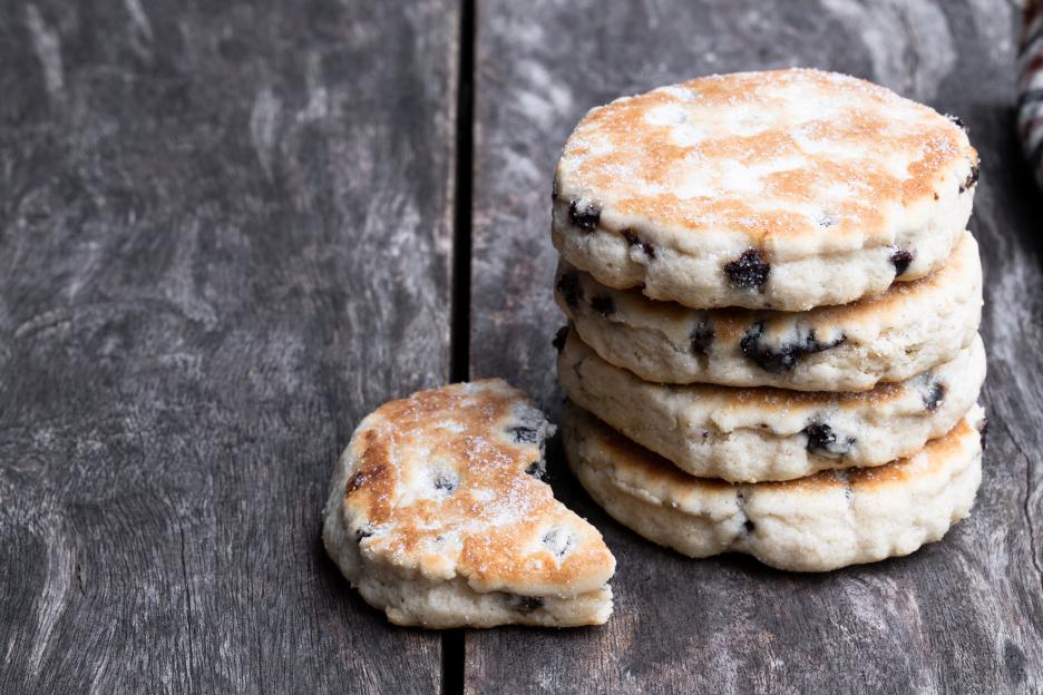 Stack of iced Welsh cakes on a wooden table.