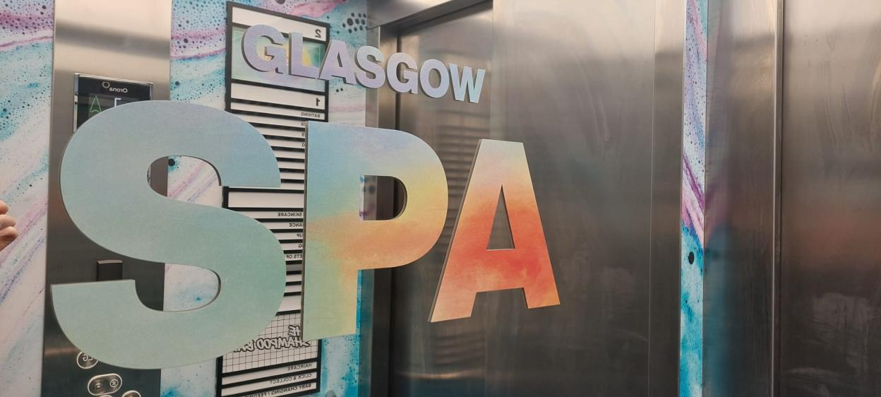 Large letters spelling out "Glasgow Spa" in front of an elevator.