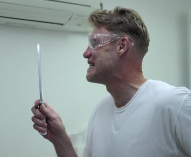 Man in safety glasses grimacing while looking at a mirror.