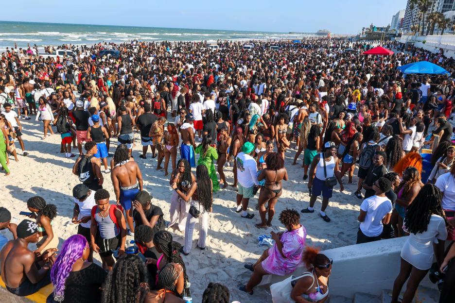 Large crowd of people partying on a beach.