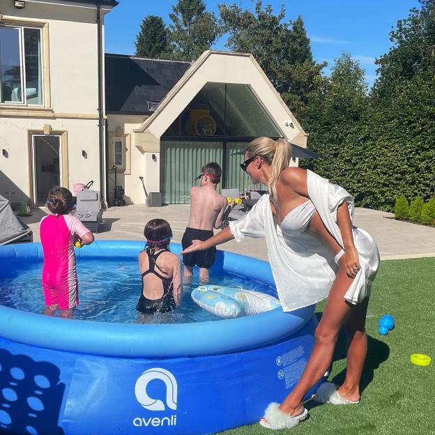 Woman and children playing in a paddling pool.