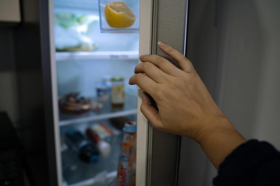 A hand reaching into a cookie jar to take a chocolate cookie.