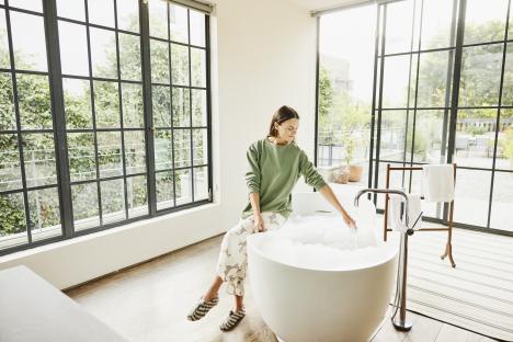 Woman relaxing in a bubble bath in a luxury hotel suite.