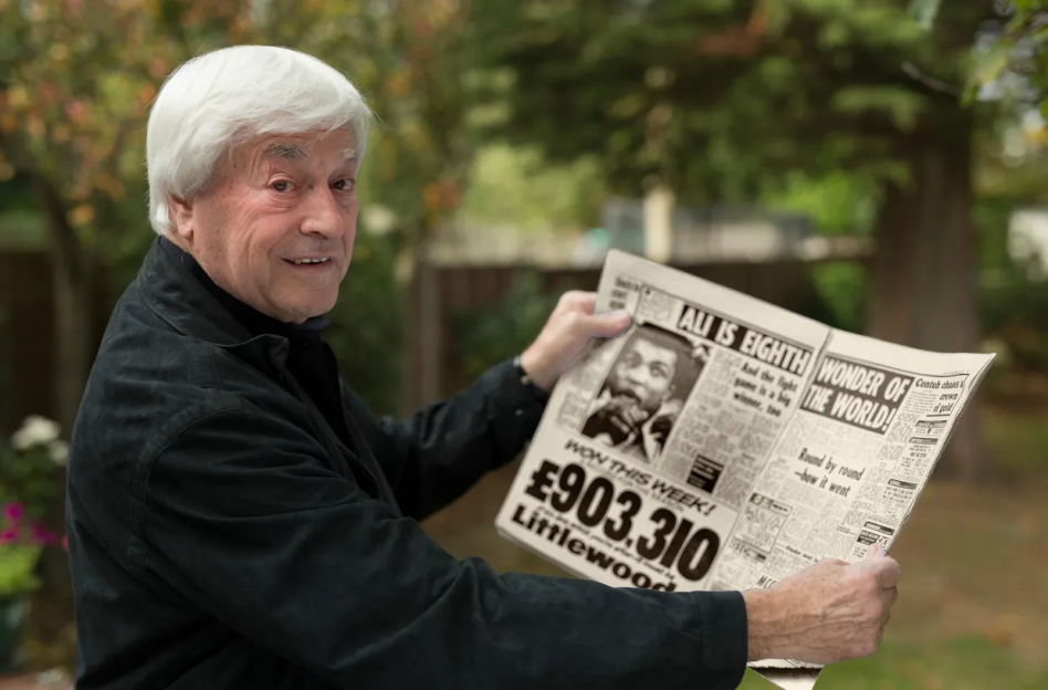 Older man holding a newspaper announcing a lottery winner.