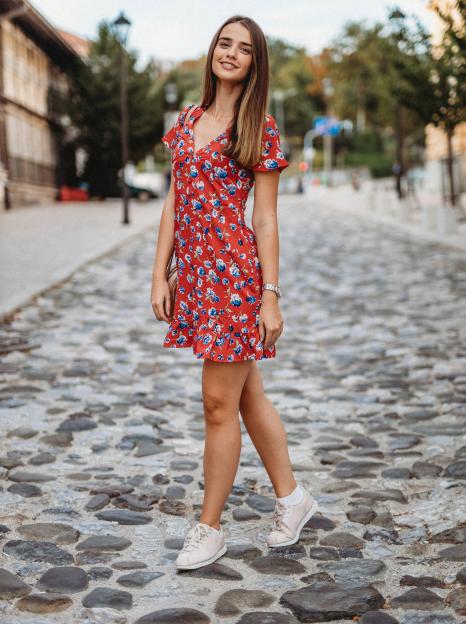 Woman in a floral dress walking down a cobblestone street.