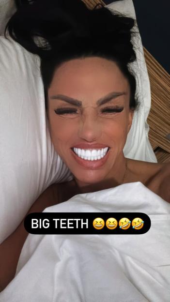 Katie Price in bed, smiling and showing off her large teeth.