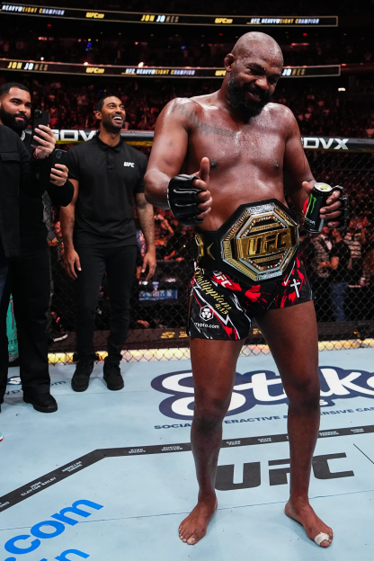 UFC fighter holding championship belt and giving thumbs up.