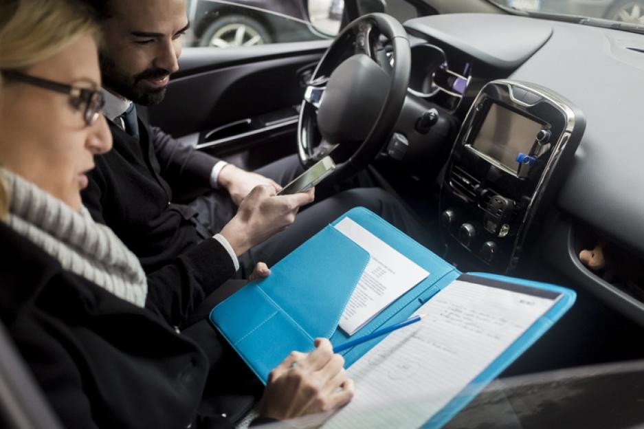 Businesspeople reviewing documents in a car.