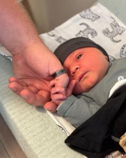 A newborn's hand grasping an adult's finger.