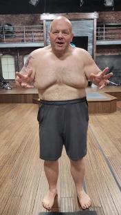 Eric Esch, shirtless, in gray shorts, standing on a scale.