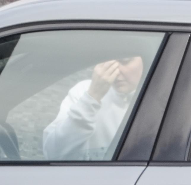 Person in a car touching their face.