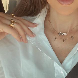 Close-up of a woman wearing gold jewelry, including a "Palma" necklace.