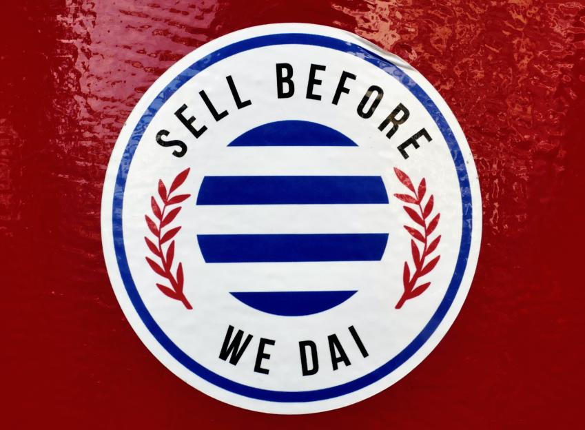 Sticker reading "Sell Before We Dai" with a blue and white striped circle and red laurel wreath.