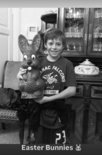 Black and white photo of a boy holding a large chocolate Easter bunny.