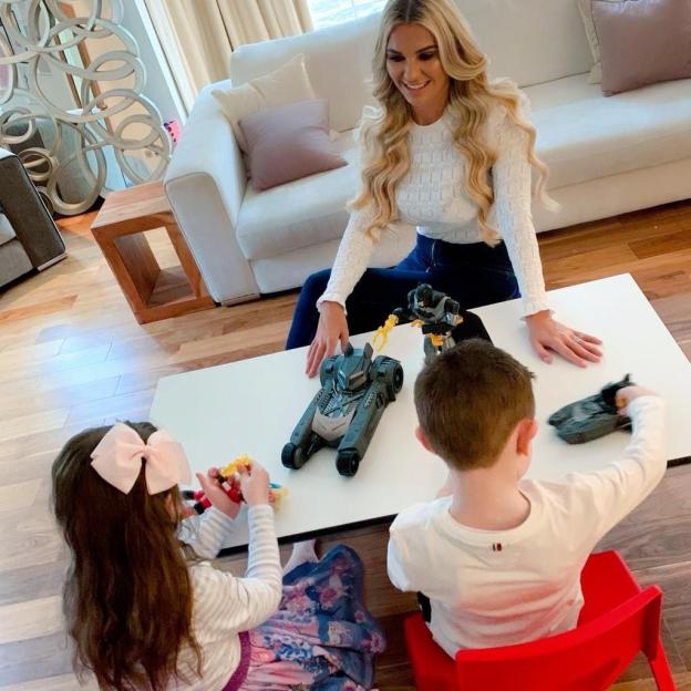 Woman playing with two children and Batman toys.