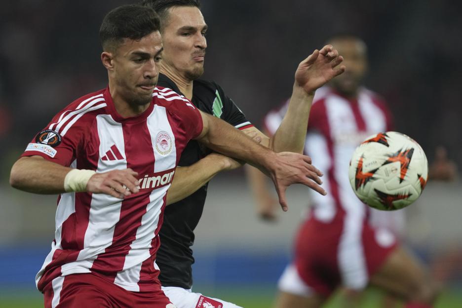 Olympiacos' Charalampos Kostoulas vying for the ball during a soccer match.