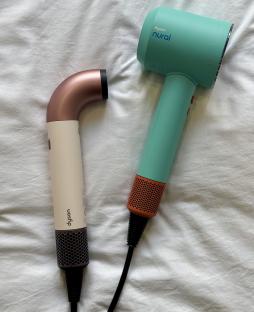 Two Dyson hair dryers in different colors.
