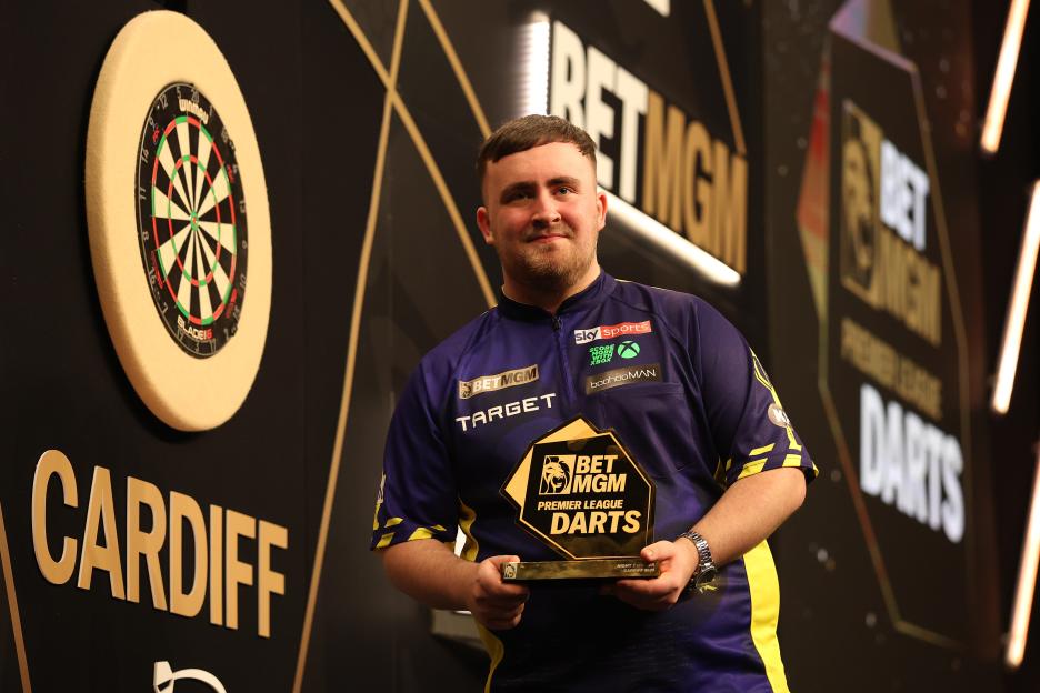 Luke Littler holding a Premier League Darts trophy.