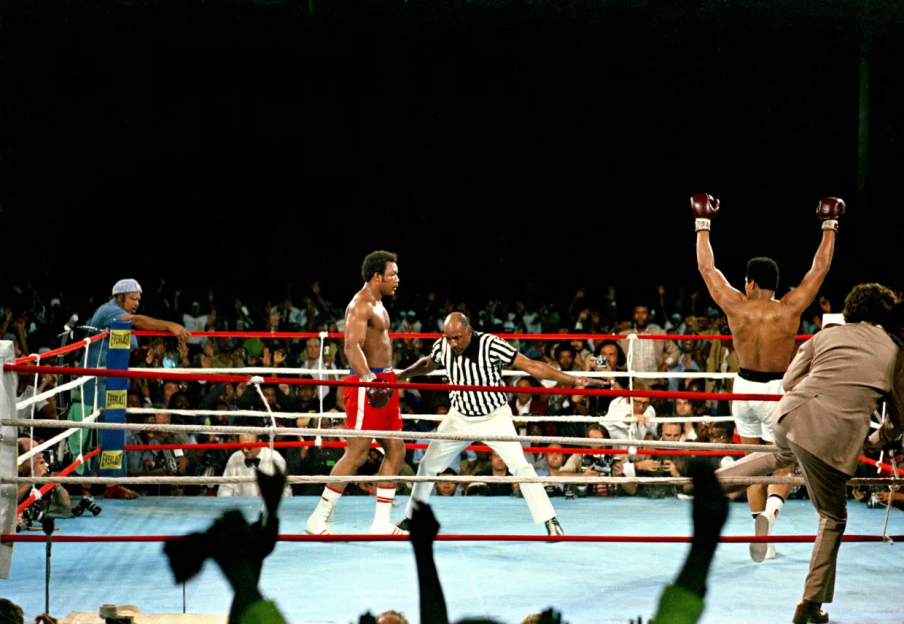 A boxer raises his arms in victory in a boxing ring.