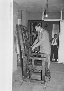 A man adjusting an electric chair in a prison.