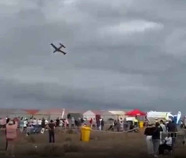 Small plane flying over a crowd of people.