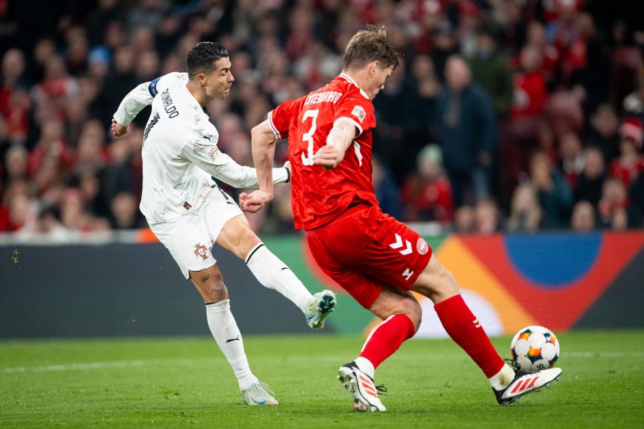 Cristiano Ronaldo of Portugal and Jannik Vestergaard of Denmark vying for the ball during a soccer match.