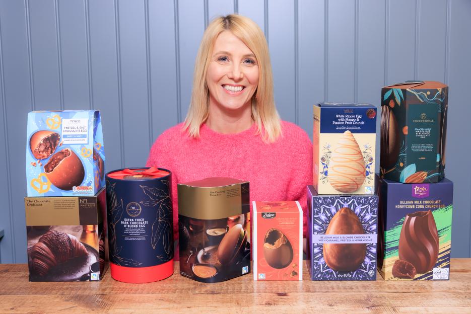 Woman smiling with various supermarket Easter eggs.