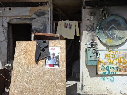 Damage to a building in Kibbutz Nir Oz, Israel, with a missing person poster.