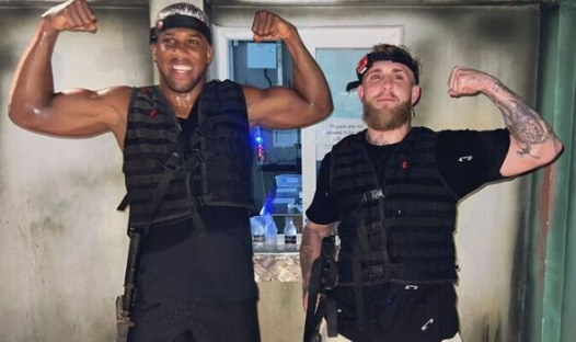 Two men in tactical vests flexing their biceps.