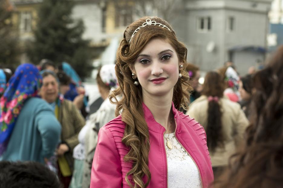 Young Roma girl in a pink jacket at a market.