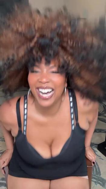 Lizzo laughing with her hair in motion.