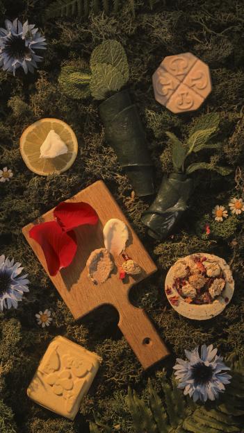 Arrangement of soaps, lotions, and flowers on moss.