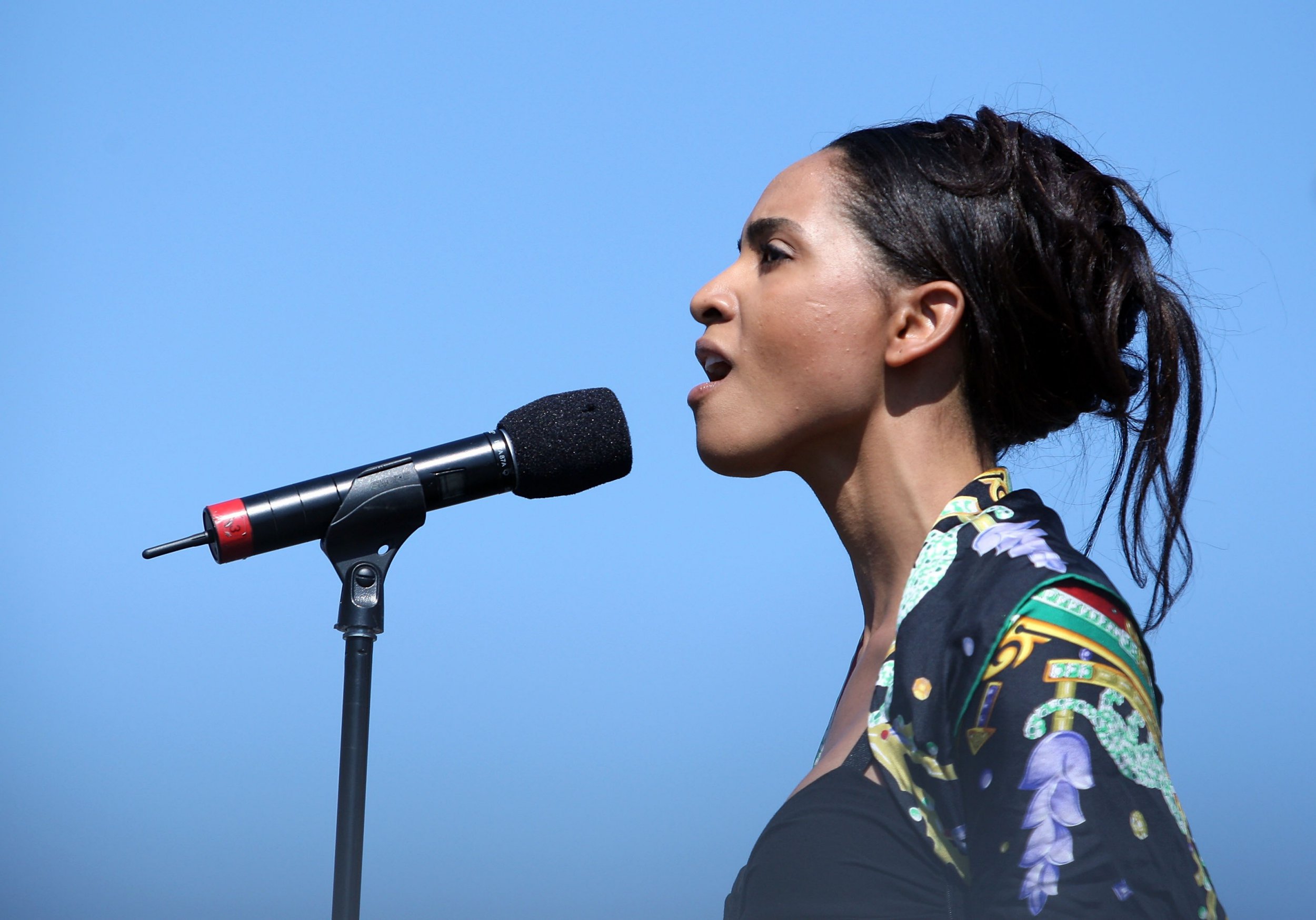 Natalie Foreman singing "God Bless America" into a microphone.