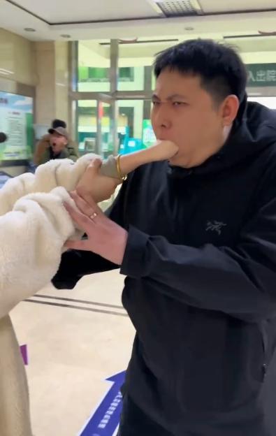 Video still of a woman's hand stuck in a man's mouth at a hospital.