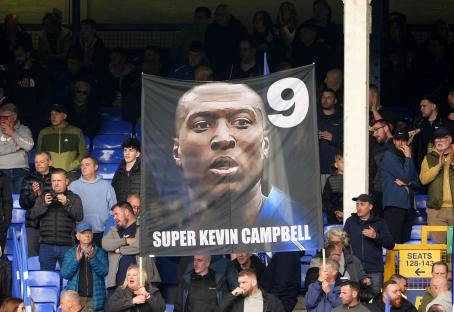 Fans holding a tribute banner for Super Kevin Campbell at a soccer match.