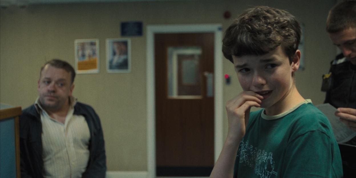 Still from *Adolescence*, showing Jamie Miller (Owen Cooper) in a tense scene with two other men.