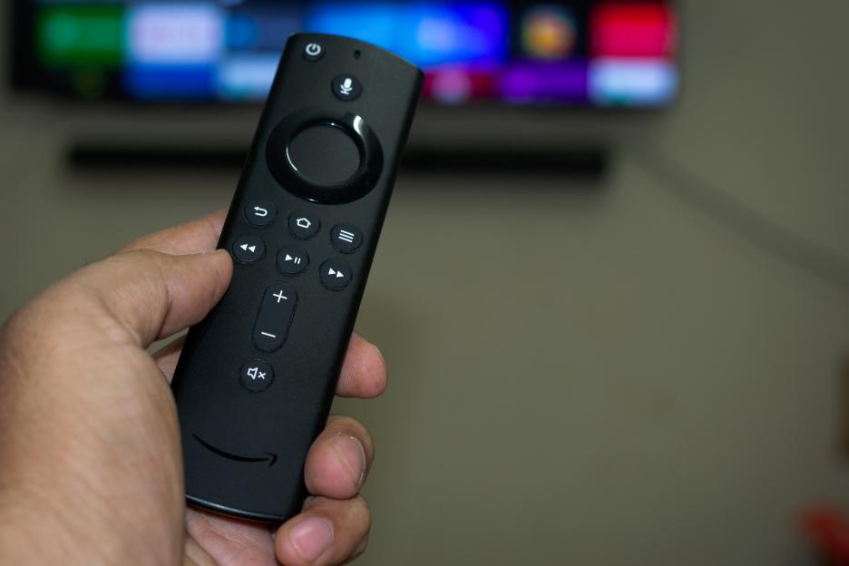 Hand holding an Amazon Fire Stick TV remote.